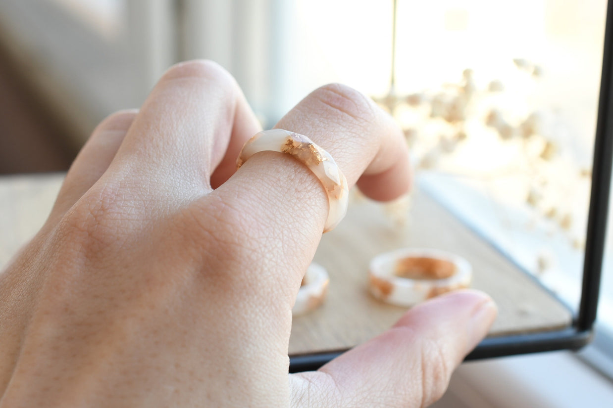 White resin ring with gold flakes worn on hand — minimalist modern jewelry