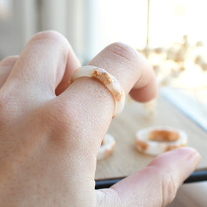 White resin ring with gold flakes worn on hand — minimalist modern jewelry