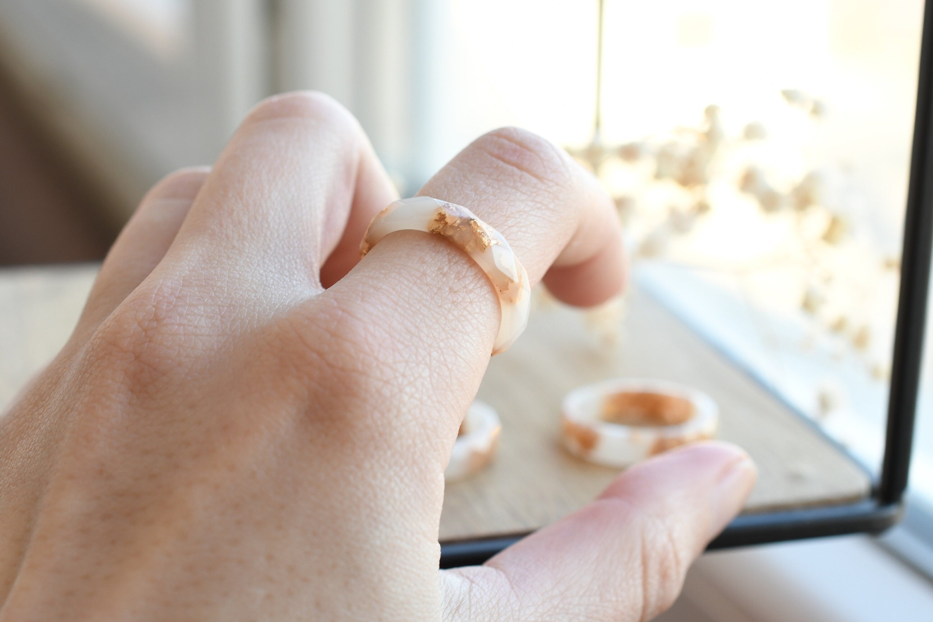 White resin ring with gold flakes worn on hand — minimalist modern jewelry