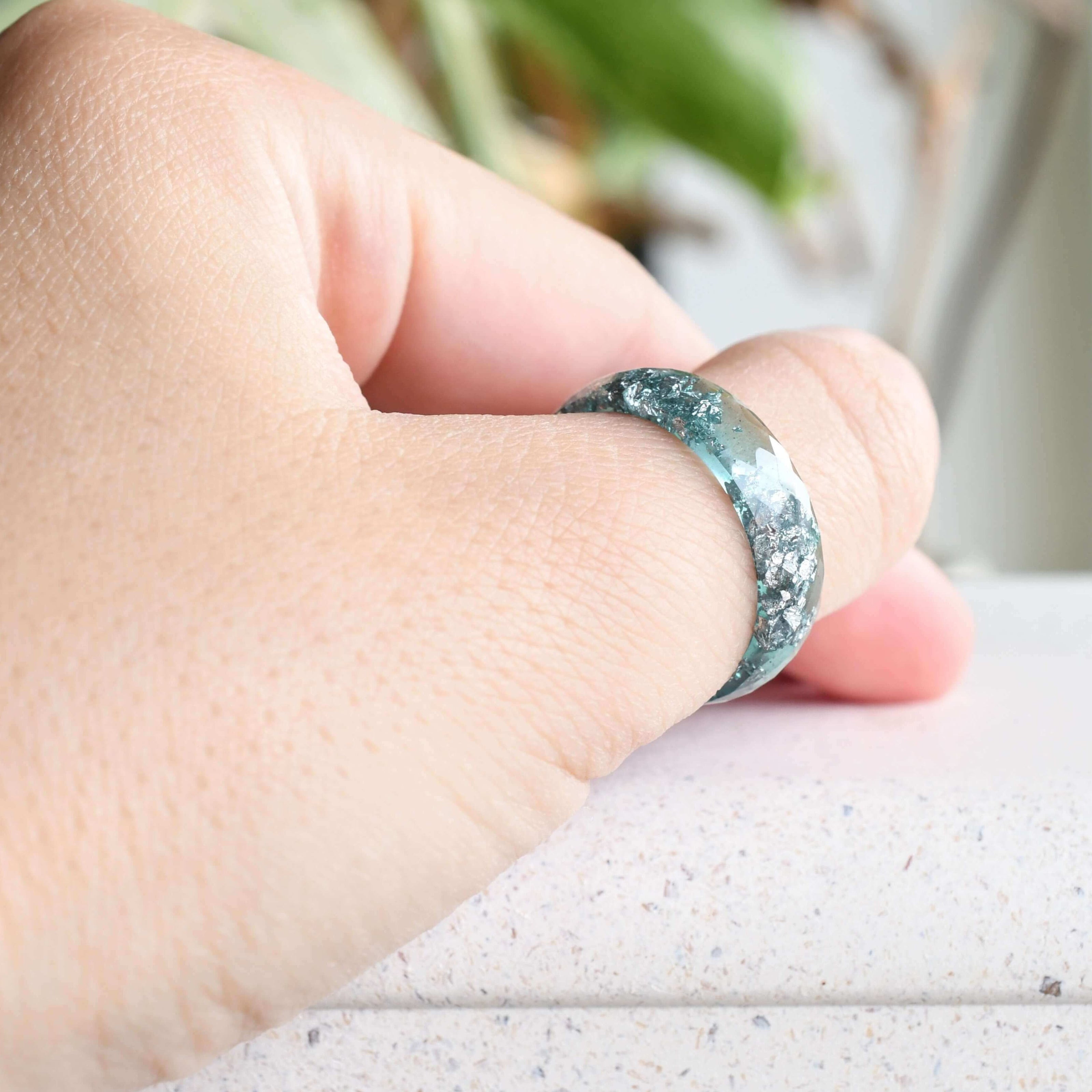 Close-up of silver flakes suspended in aquamarine resin handmade ring