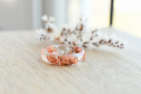 Transparent resin ring with copper flakes on wooden background