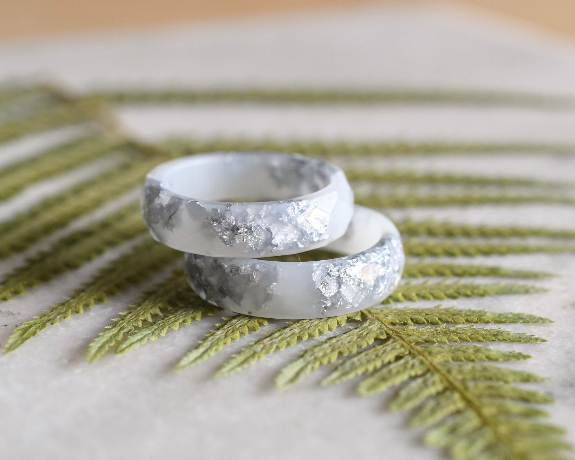 Close-up of silver flakes suspended in opaque white resin handmade ring