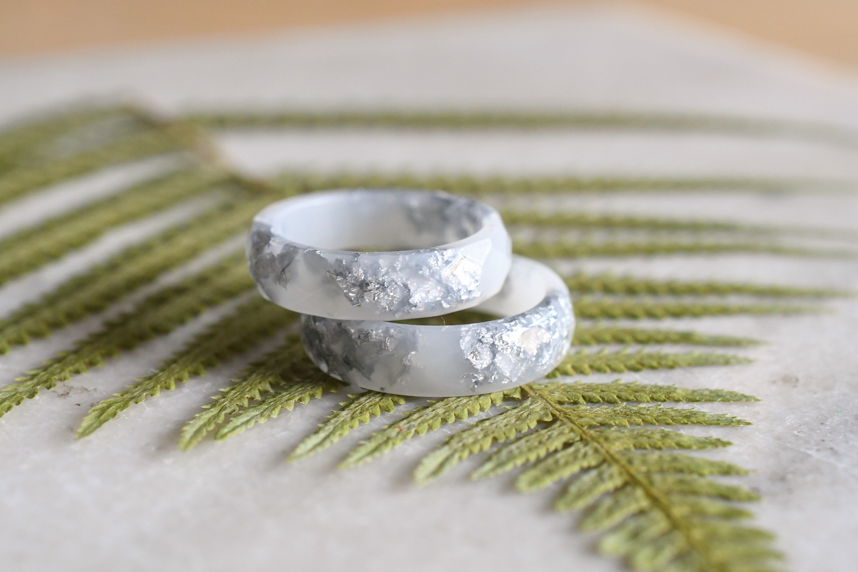 Close-up of silver flakes suspended in opaque white resin handmade ring